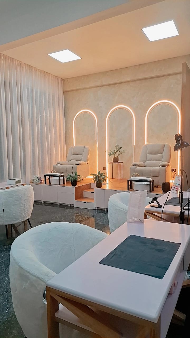 Sala de pedicura de Nails Home con sillones beige y arcos iluminados